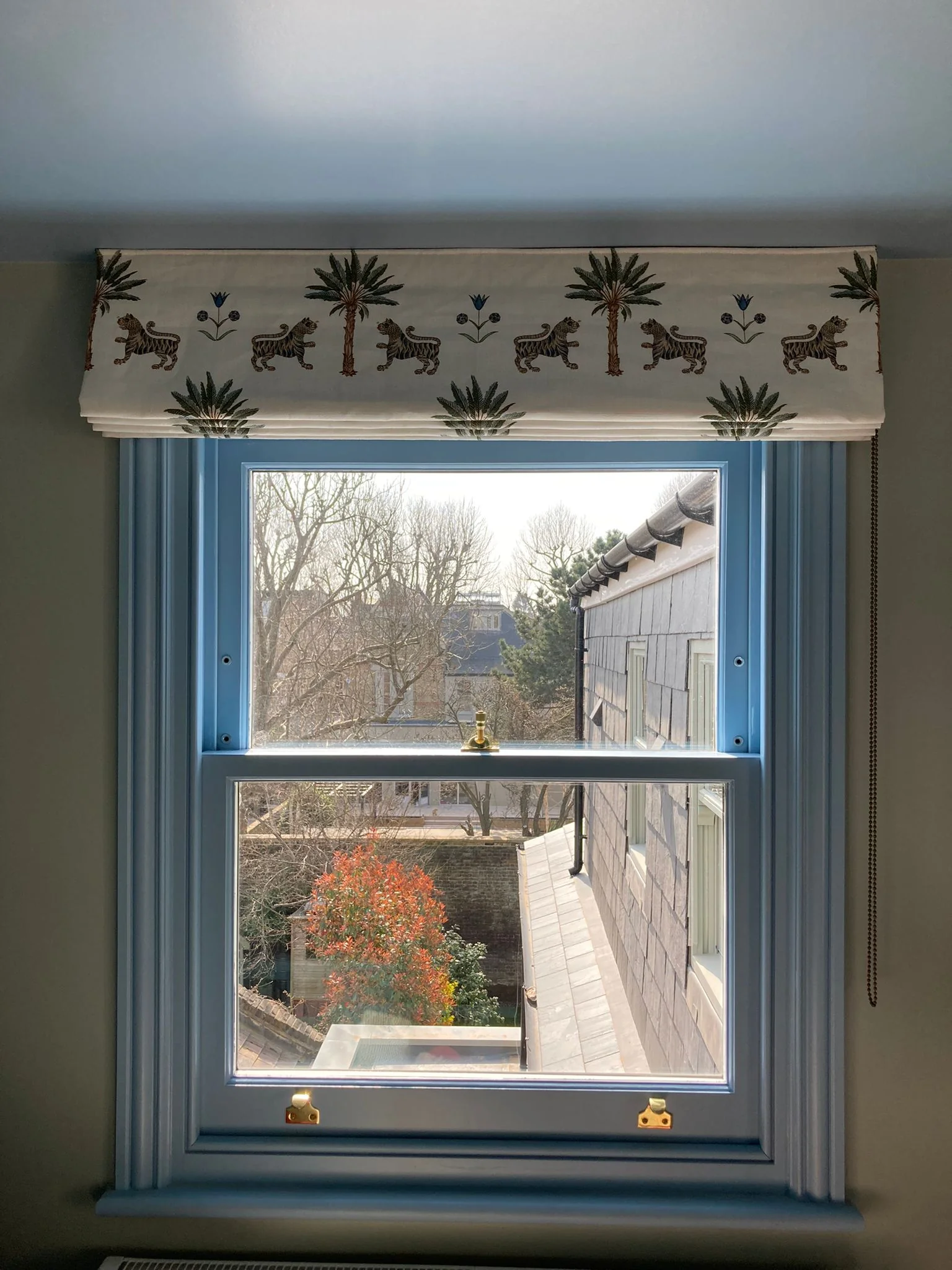 Made to measure Roman blind dressing a window in a blue London living room