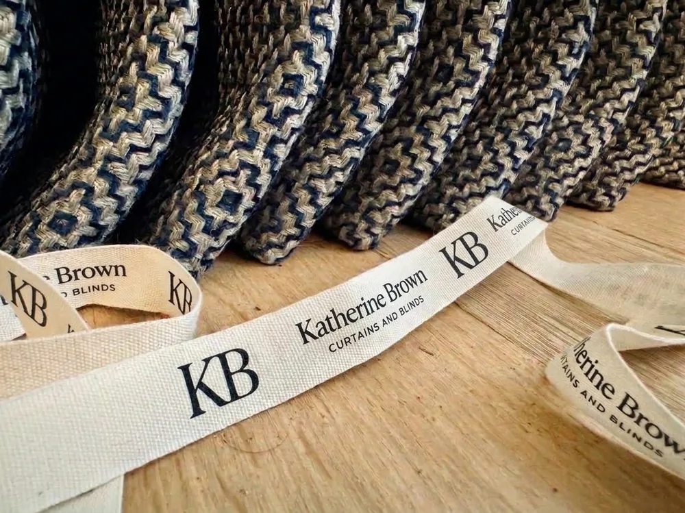 Katherine Brown branded ribbon tied around rolls of woven curtain fabric